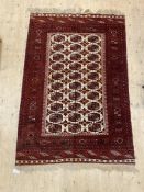 A hand knotted Bokhara rug, the ivory field with lozenge and gul motif within a guarded border 210cm