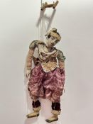 A 1920's carved wood Burmese male puppet with inset glass eyes dressed in later short wasted