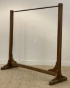 An Edwardian coat rack, the brass rail raised on two fluted square section columns united by a