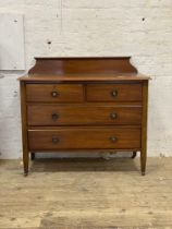 An Edwardian walnut ledge back chest, fitted with two short and two long drawers, raised on square
