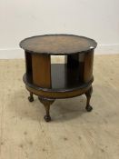 A 1930's burr walnut revolving book table, the circular top with scalloped edge, raised on
