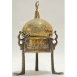 An Eastern brass tripod censer with chased Arabic inscriptions and crescent moon finial, possibly
