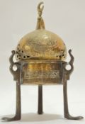 An Eastern brass tripod censer with chased Arabic inscriptions and crescent moon finial, possibly