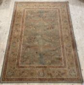 A Persian style machine-loomed rug, the faded green ground of floral design enclosed by a guarded