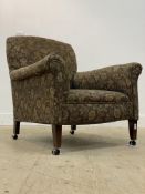 An early 20th century upholstered easy chair, raised on square tapered supports terminating in later