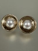 A pair of 9ct gold mabe pearl earrings mounted in rub over setting within a planished border D x 2.