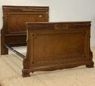 An Edwardian walnut panel end double bed frame, the head and foot well carved with paterae,