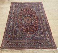 A hand knotted Persian rug, early 20th century, the red field with floral medallion and