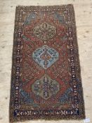 An early 20th century Persian Heriz design rug, the red field with triple medallion and decorated