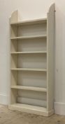 An early 20th century white painted pine floor standing open bookcase. H140cm, W62cm, D18cm.