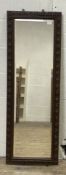 An early 20th century wall hanging mirror, the frame carved with a repeating flower head and