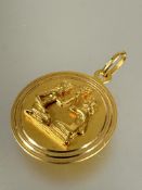 A 18ct gold circular pendant with two kneeling figures holding an olive branch with chain loop to