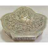 An Indian embossed/repousse white metal lidded box with scrolling foliate designs and peacocks,