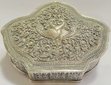 An Indian embossed/repousse white metal lidded box with scrolling foliate designs and peacocks,