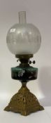An Edwardian oil lamp, the cast brass base supporting a green glass reservoir hand enamelled with