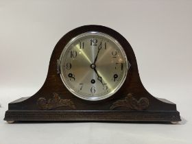An early 20th century Hermle triple chain mantel clock, the arched oak case with scrolling