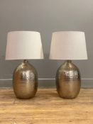 A pair of contemporary planished metal lamp bases, each complete with an oatmeal linen shade. H60cm.