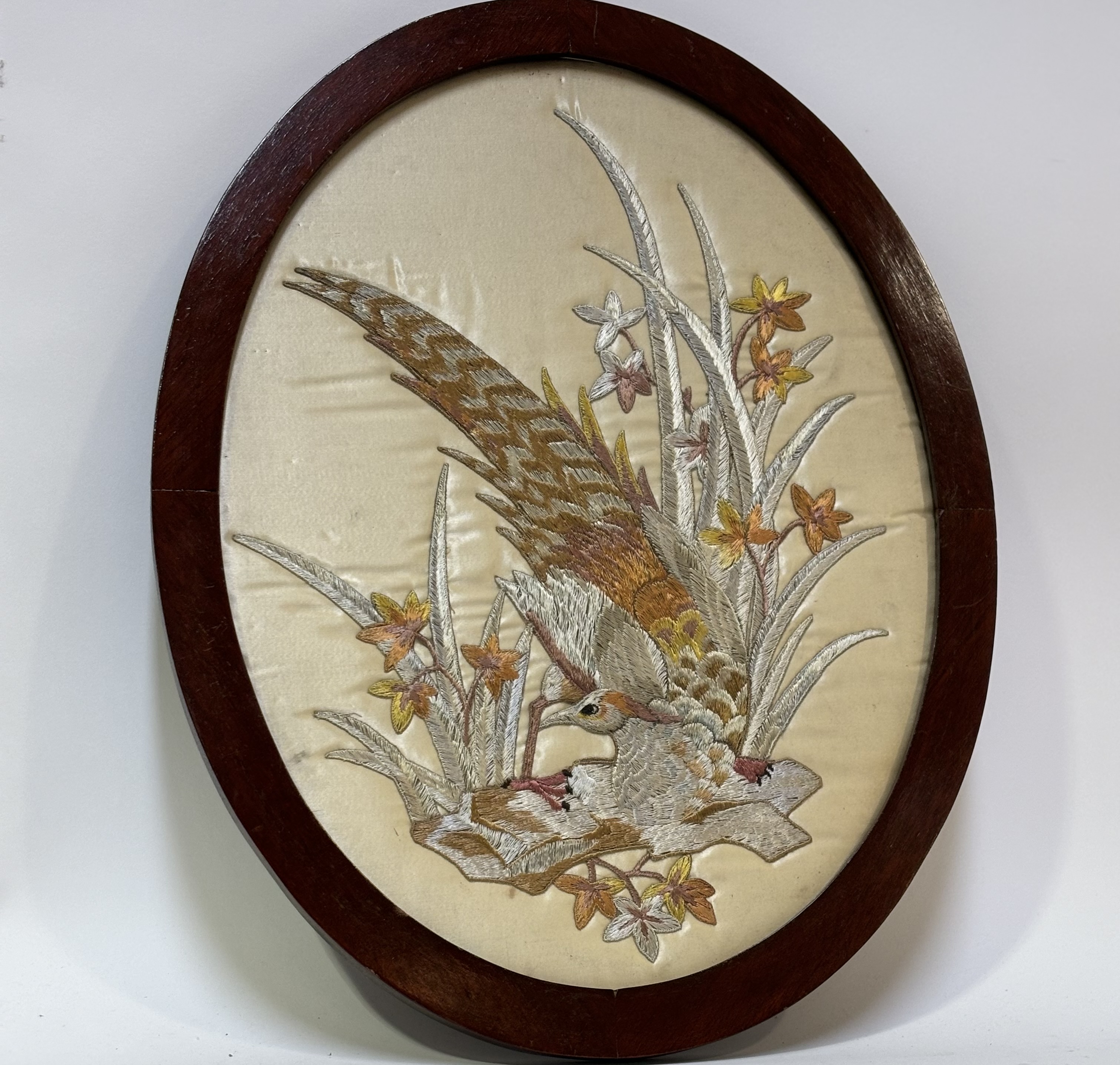 A decorative oval sewn work panel on silk of a silver pheasant, framed. (46cmx35cm)