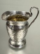 A Edwardian Art and Crafts London silver individual milk jug with planished finish and C scroll