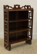 An early 20th century mahogany three height open bookcase with fret carved decoration, standing on