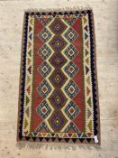 A vintage kilim rug, the red field with geometric pole medallion within a border having a