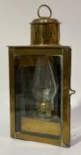 A 19th century brass reflector oil lamp, with swing handle above a glazed triangular case and wall