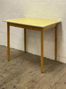 A 1950's beech and yellow Formica kitchen table, on turned and tapered supports. H76cm, 61cm x 81cm.