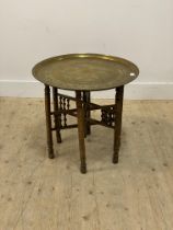 An early 20th century eastern occasional table, the circular brass tray top engraved with arabesques