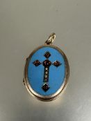 A victorian yellow metal oval locket with gem and seed pearl set cross in turquoise enamel panel