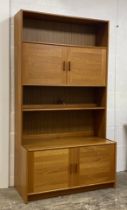 A mid century teak bookcase cabinet, fitted with two cupboards above an illuminated shelf, the