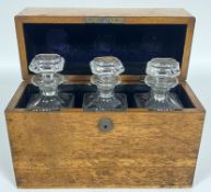 An early twentieth century leather lined oak spirits container/tantalus with three clear glass