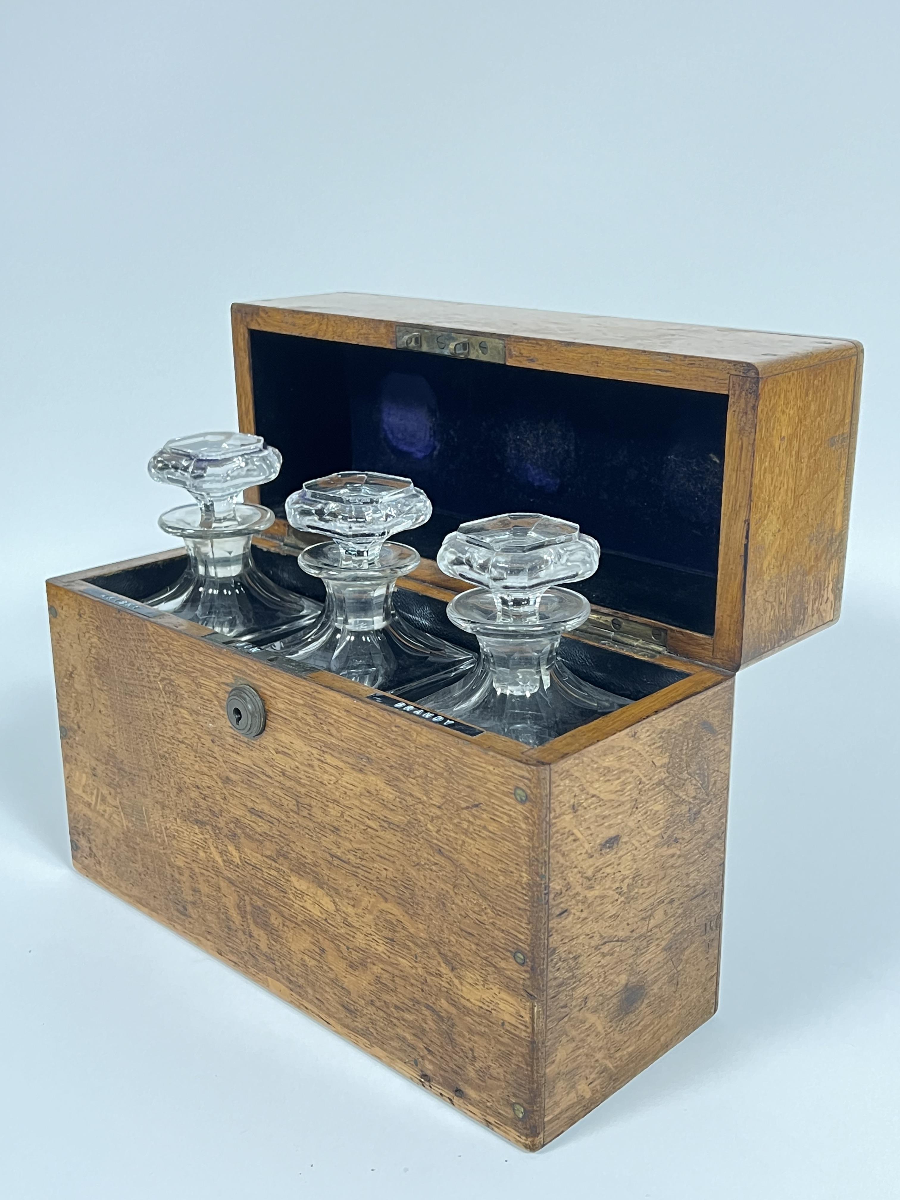 An early twentieth century leather lined oak spirits container/tantalus with three clear glass - Image 2 of 4