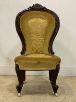 A Victorian strained walnut spoon back slipper chair, with floral carved crest above upholstered