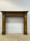 A Victorian pitch pine fire surround in Neoclassical style, the inverted breakfront top over two