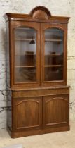 A Victorian mahogany bookcase, the arched cornice above two glazed doors enclosing three