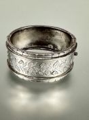 A Edwardian silver cuff style Birmingham silver hinged bracelet with leaf and flower engraved