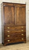 A Regency mahogany linen press, the figured frieze over two doors with beeded moulding and brass