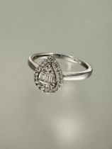 A 9ct white gold ring of heart shape, the center set three baguette cut diamonds and three diamond