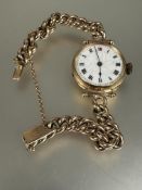 A Edwardian 9ct gold ladys wristwatch with white enamel dial and roman numerals with engraved
