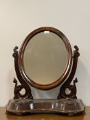 A Victorian mahogany vanity mirror, the oval mirror swivelling between two floral carved uprights,