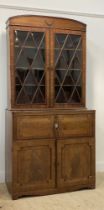 A late Regency mahogany secretaire bookcase, the arched and reeded cornice above an ebony strung