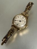 A ladys 9ct gold wrist watch with silvered dial subsidiaries dial on expanding gilt metal bracelet