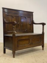 An early 20th century oak hall bench, the twin geometric panelled high back above two scrolled