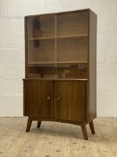A mid century walnut bookcase, with two glazed sliding doors enclosing two adjustable shelves, above