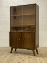 A mid century walnut bookcase, with two glazed sliding doors enclosing two adjustable shelves, above