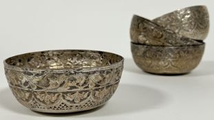 A set of four silver or white metal Malaysian bowls with scrolling foliate repousse decoration and