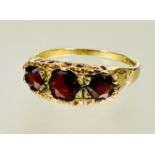 A 9ct gold graduated three stone circular garnet set ring center stone approximately 0.33ct N 2.06g