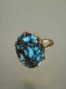 A yellow metal ring set oval turquoise nugget of domed shape mounted in six claw setting T/U L x 2cm
