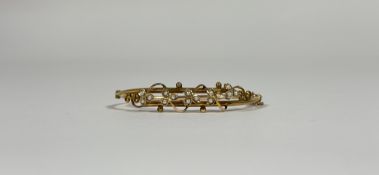 An Edwardian gold (unmarked) and seed pearl hinged bangle, set to one half with open scrollwork