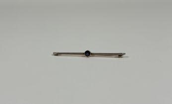 A 15ct gold bar brooch set with a sapphire, the knife-edge bar set to the centre with a millegrain-